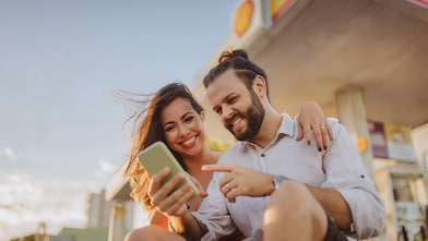 Usměvavá slečna si dává občerstvení a kouká do svého mobilu.