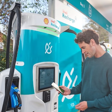 Mladý muž platí u stojanu za využití nabíjecí stanice Shell Regcharge