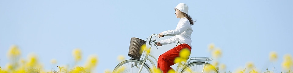 Mladá žena jede na kole letním polem.