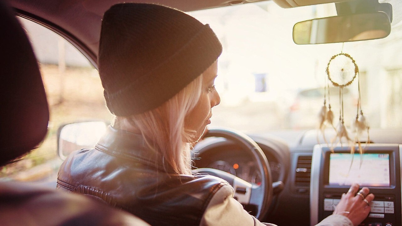 A young woman checks the instructions displayed on her car's built-in navigation screen