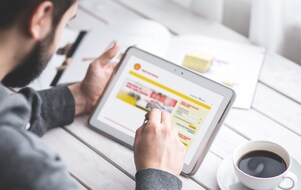 Někoho, kdo pracuje na jeho tabletu. Online portál Shell Card je na obrazovce tabletu.