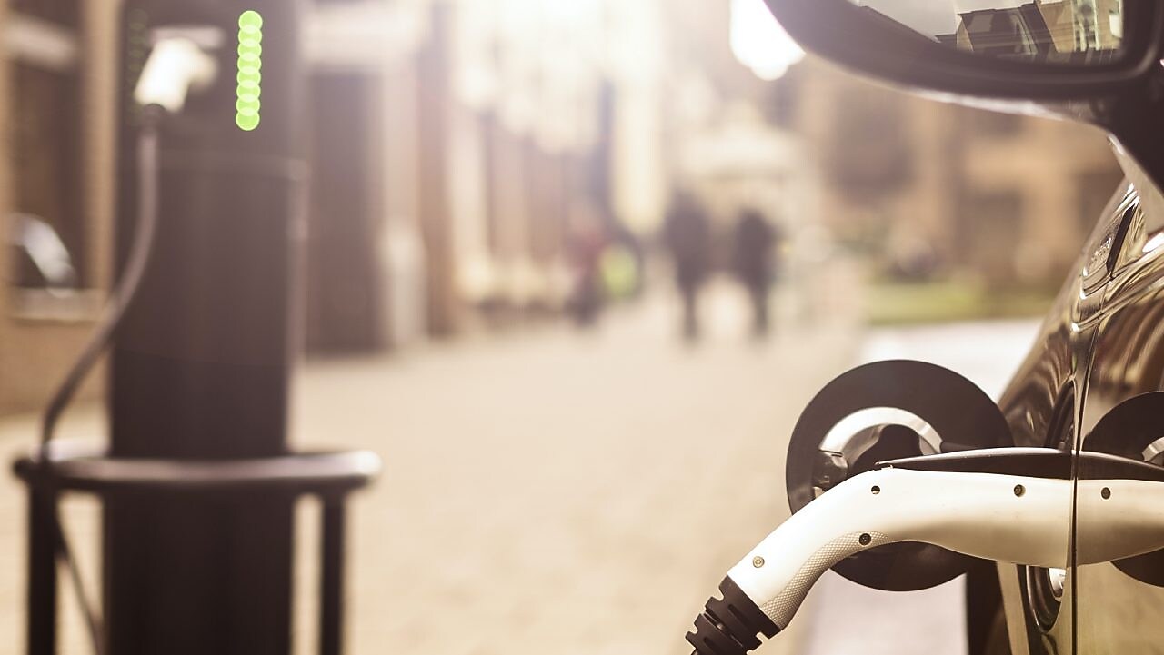 Černé auto se nabíjí za pomoci konektoru.