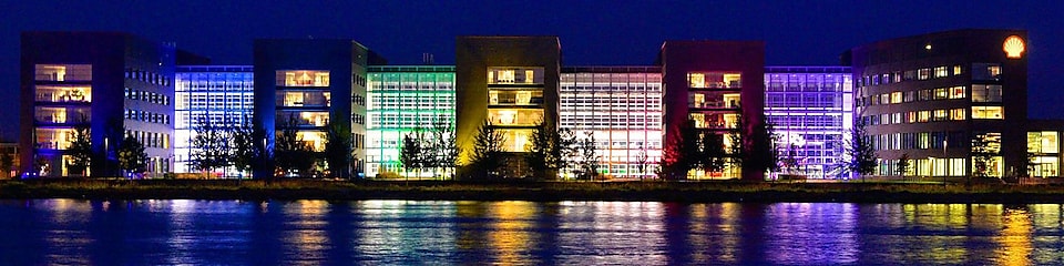 Několik osvětlených kancelářských budov se odráží v&nbsp;noci ve vodě