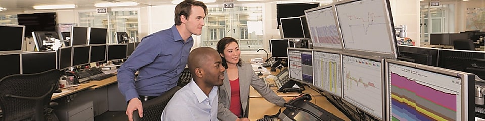 Zaměstnanci tradingu zkoumají data na několika počítačových obrazovkách