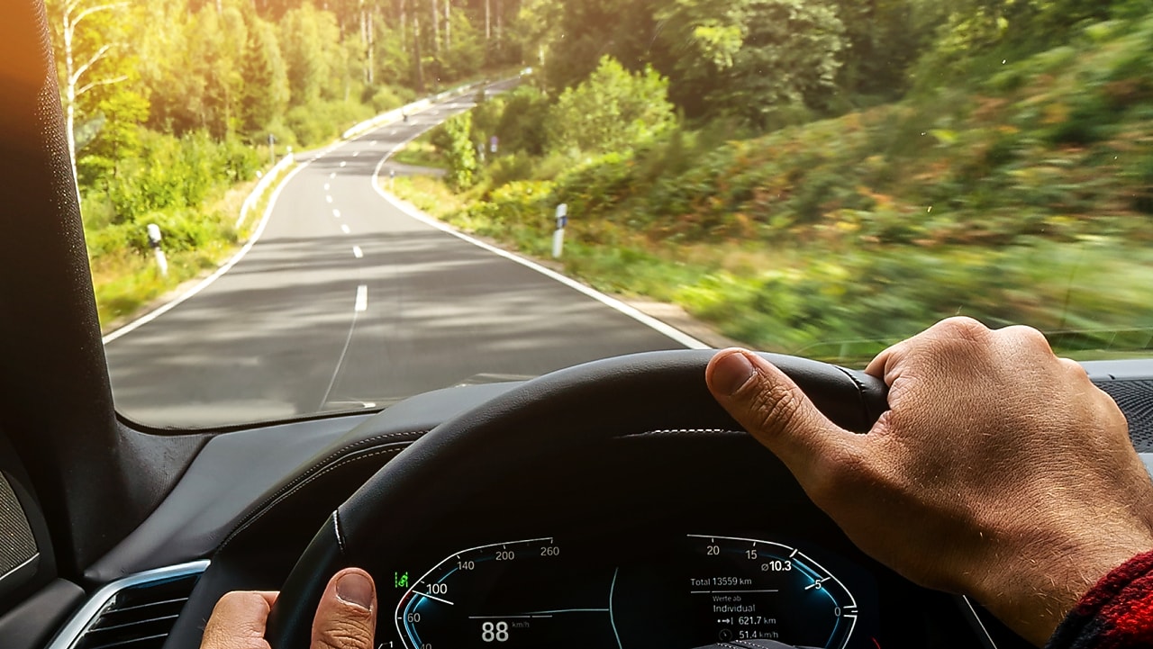 Pohled řidiče zevnitř auta na čisté čelní sklo a krajinu kolem.