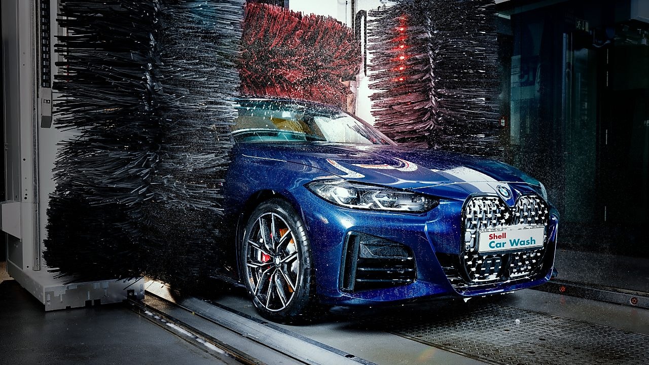 Modré auto v detailu projíždí Shell automyčkou.