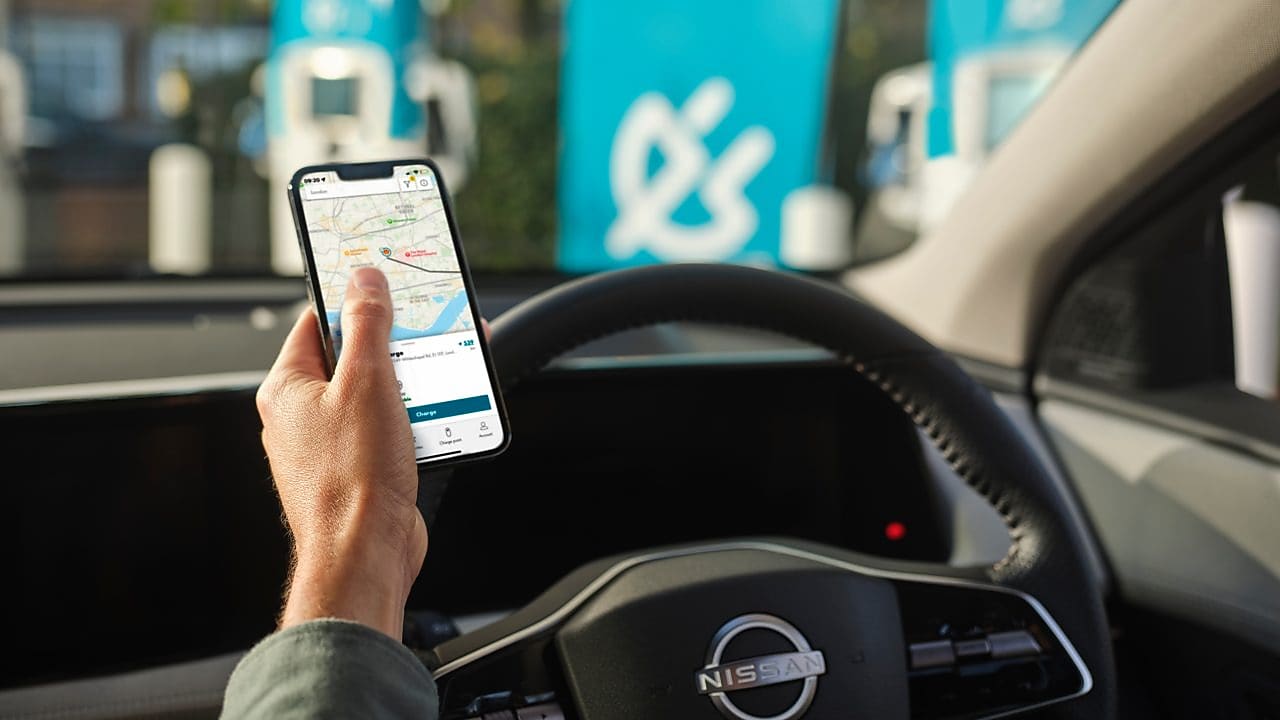 Muž v autě právě zaparkoval u dobíjecí stanice Shell Recharge.