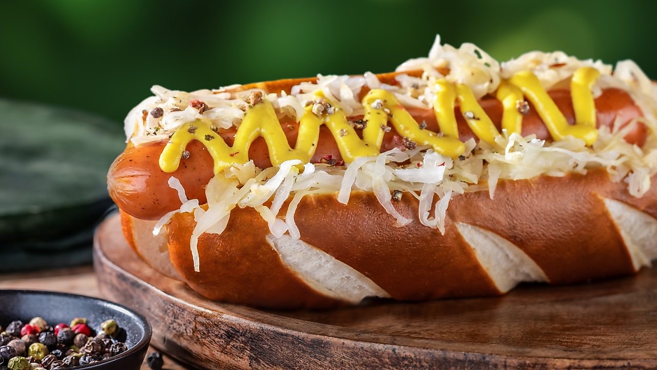 Foto sedláckého hot dogu s nivou, kysaným zelím a hořčicí