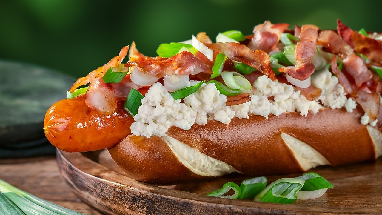 Foto brynzového hot dogu s anglickou slaninou, jarní cibulkou a brynzou