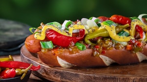 Foto hot dogu Německo s hořčicí, okurkovým relishem, jarní cibulkou a beraními rohy