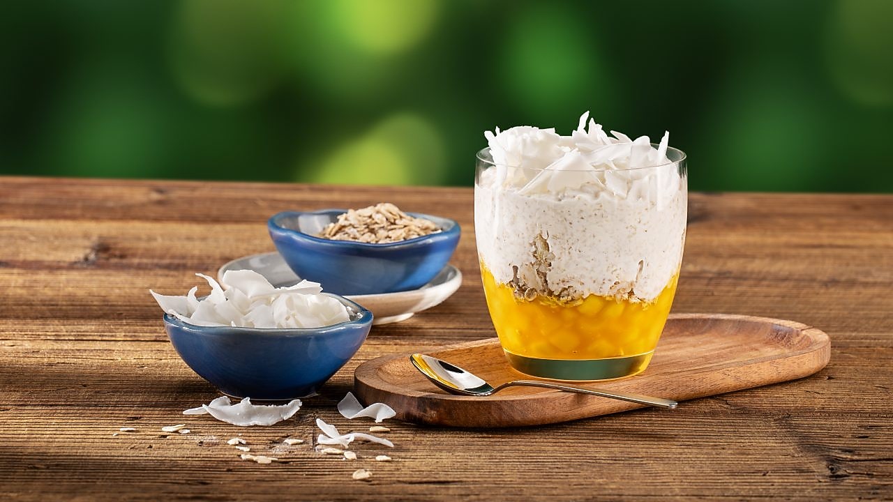 Foto ovesné kaše ve skleněném poháru s mangem a kokosem